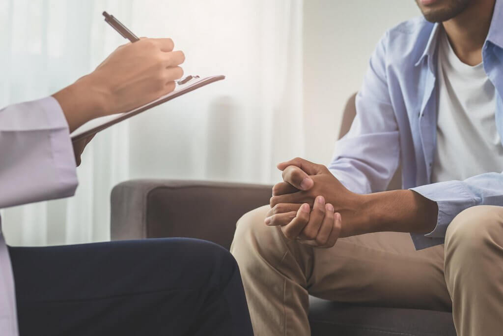 A close up of a person taking notes on a clipboard while sitting across from a person. This could symbolize the support an anxiety therapist in Branchburg, NJ can offer in addressing food allergies and anxiety. Learn more about anxiety treatment in Branchburg, NJ by searching for "therapist branchburg, nj" today. 
