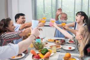 A family toasts while smiling at a dinner table. Learn how counseling in Branchburg, NJ can offer help by searching for therapist branchburg, nj or “therapy branchburg, NJ” for more information.