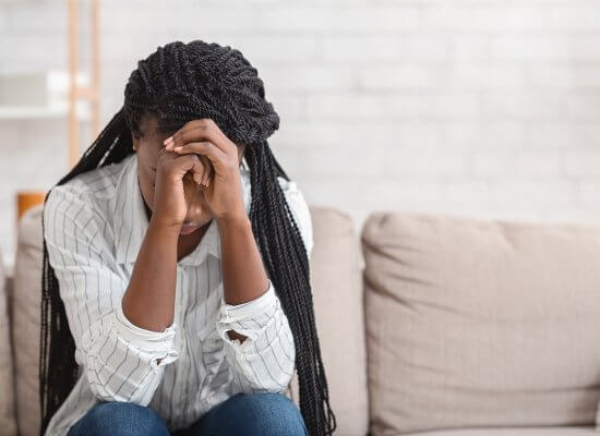 A woman covers her face while sitting in a dark room. This could represent the pain of trauma that a trauma therapist in Scotch Plains, NJ can address. Learn more about trauma therapy in Branchburg, NJ and the help EMDR trauma therapy in Scotch Plains, NJ can offer.