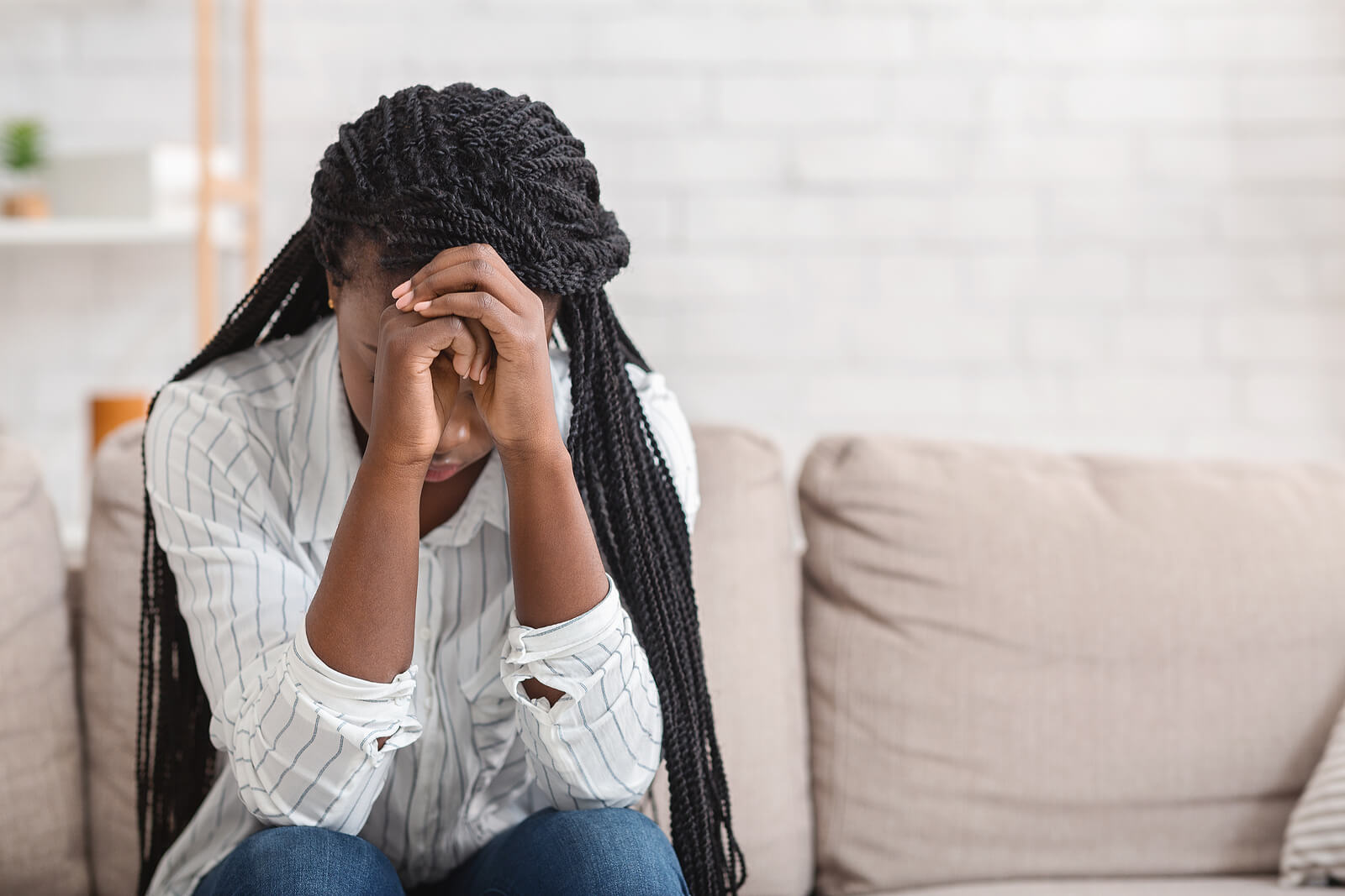 A woman covers her face while sitting in a dark room. This could represent the pain of trauma that a trauma therapist in Scotch Plains, NJ can address. Learn more about trauma therapy in Branchburg, NJ and the help EMDR trauma therapy in Scotch Plains, NJ can offer.