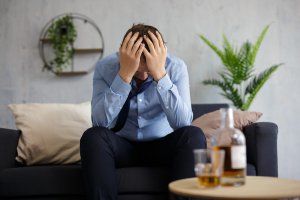 A man covers his face while sitting in front of a liquor bottle. Learn how a couples counselor in Branchburg, NJ can offer support with you and your partner with overcoming addiction. Search for couples therapy in Scotch Plains, NJ and other services. 