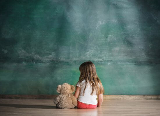 A child sits alone with a bear while facing a wall. Learn how a trauma therapist in Scoth Plains, NJ can offer support with parenting help in Scotch Plains, NJ or addressing past trauma. Search for trauma therapy in Branchburg, NJ today.
