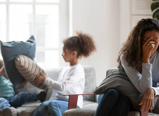 A mother covers her face as her kid’s pillow fights in the background. Learn how a moms support group in Branchburg, NJ can offer support with online therapy in New Jersey and other services. Contact a group therapist in Scotch Plains, NJ to learn more.