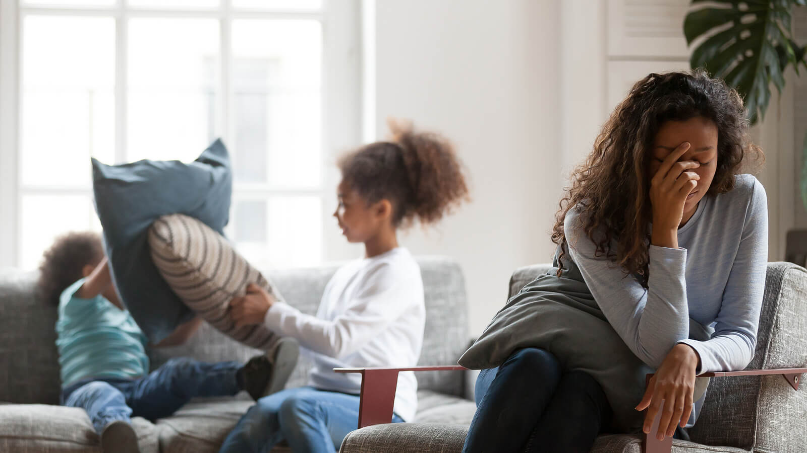 A mother covers her face as her kid’s pillow fights in the background. Learn how a moms support group in Branchburg, NJ can offer support with online therapy in New Jersey and other services. Contact a group therapist in Scotch Plains, NJ to learn more.