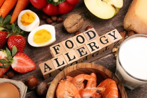 A close up of the word food allergies supprounded by different foods. Get support for food allergies and anxiety by seaching for an anxiety therapist in Branchburg, NJ. Learn more about teens with food allergies New Jersey today.