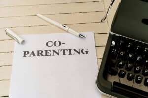 Co-parenting sketched on paper beside a typewriter, promoting therapy services in Scotch Plains, NJ.