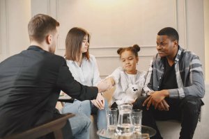 A man and woman shake hands, with a young girl present, illustrating partnership in food allergy anxiety therapy in NJ.