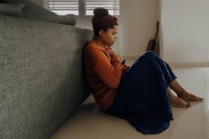 A person sitting alone against a couch, appearing distressed, illustrating the isolation of food allergy anxiety. Therapy services in Scotch Plains NJ help individuals and their supporting spouses navigate emotional challenges while advocating for proper food allergy management.
