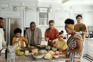 Family in Branchburg kitchen preparing allergen-safe meals together, with grandparents learning proper food separation techniques while bonding with grandchildren over cooking activities