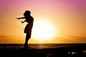 : Silhouette of a person with outstretched arms on a pier at sunset, symbolizing freedom and empowerment. Therapy for ADHD in adult women near Somerville, NJ, helps women thrive by embracing their unique strengths.