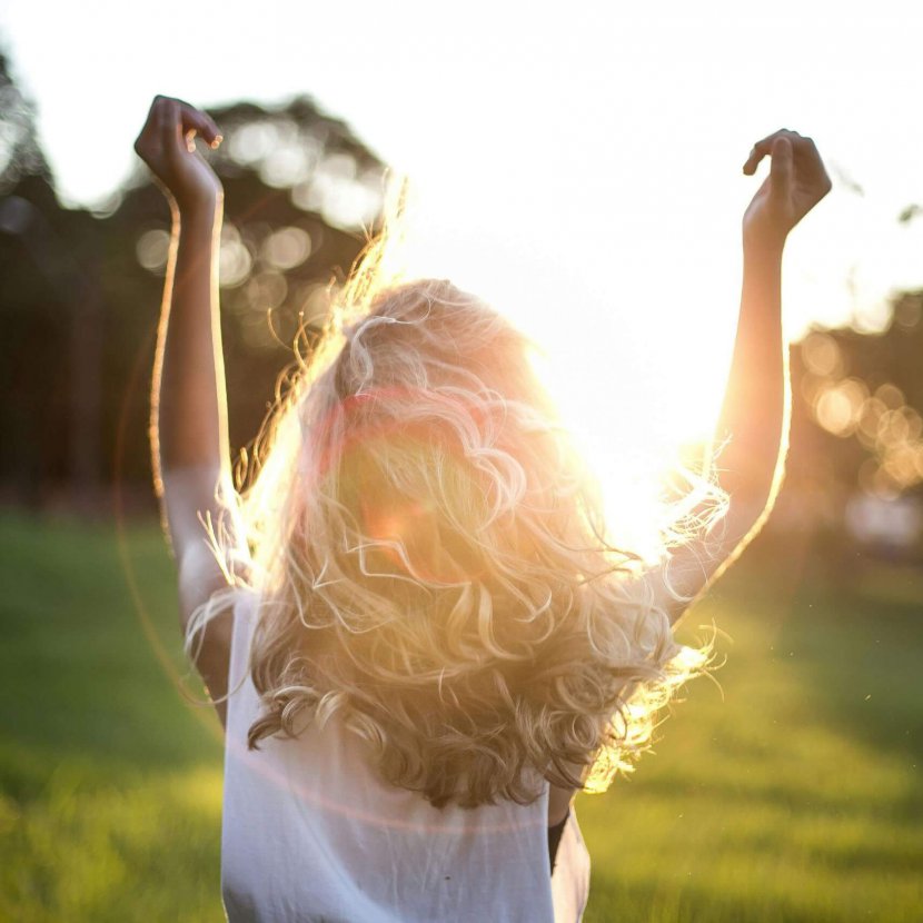 A backlit photograph of a person with curly hair raising their arms in celebration against a sunset background, representing the freedom and joy that comes from therapeutic support for neurodivergent individuals reclaiming their identity and sexuality in Branchburg and surrounding areas.