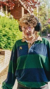 Neurodivergent adult wearing headphones outdoors, symbolizing sensory support and inclusion through neurodiversity affirming therapy in New Jersey with a therapist for neurodivergent adults in New Jersey.