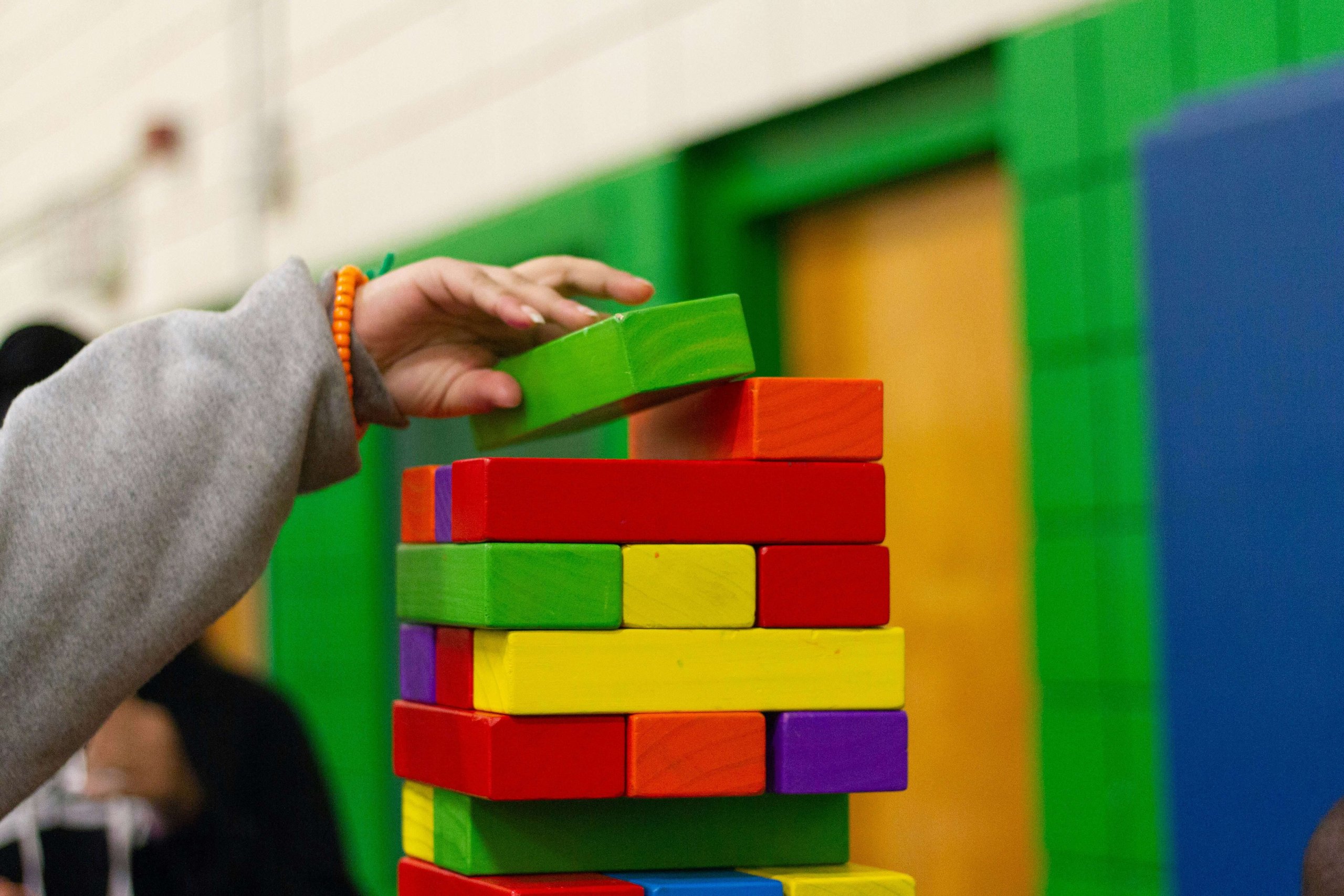 A child stacking colorful wooden blocks during a play therapy session in Scotch Plains, NJ. Serving families in Branchburg, Somerville, and surrounding New Jersey communities seeking child counseling.