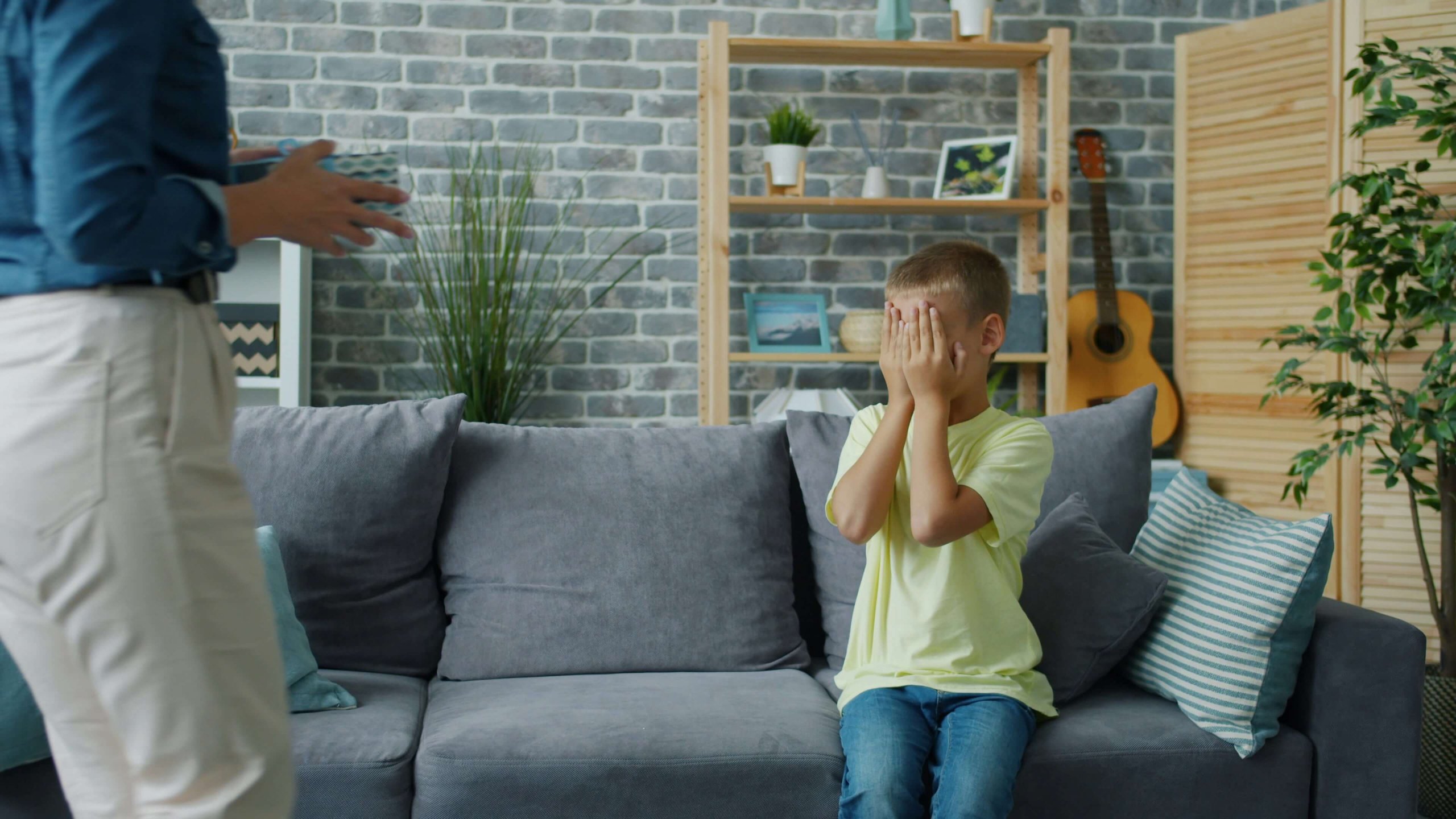A young boy covering his face on a couch, reflecting the emotional struggle of therapy resistant children in NJ. Serving parents in Scotch Plains, Branchburg, and Somerville looking for parenting advice and parent coaching in Scotch Plains, NJ.