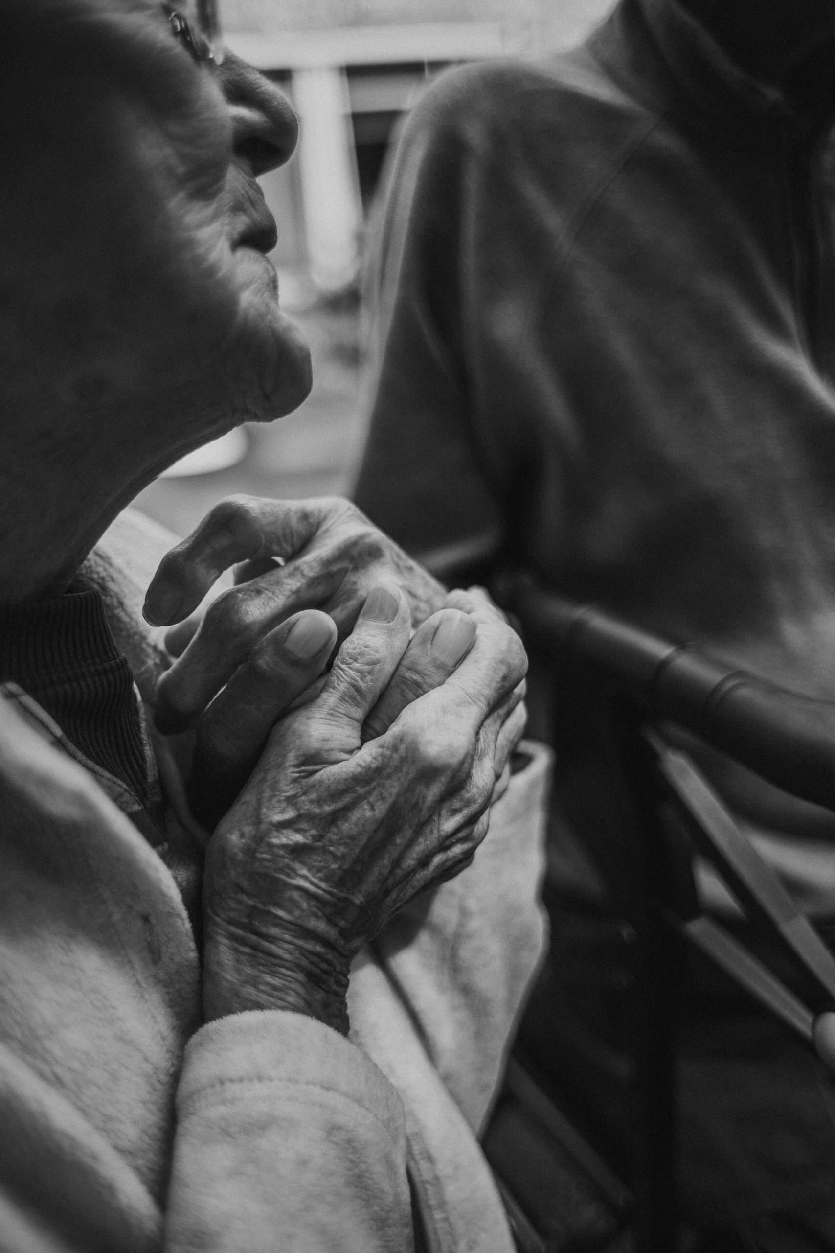 A tender black and white close-up of hands clasped together in Branchburg. Serving Branchburg, NJ families seeking how to support someone with cancer through steady, compassionate presence during difficult moments.